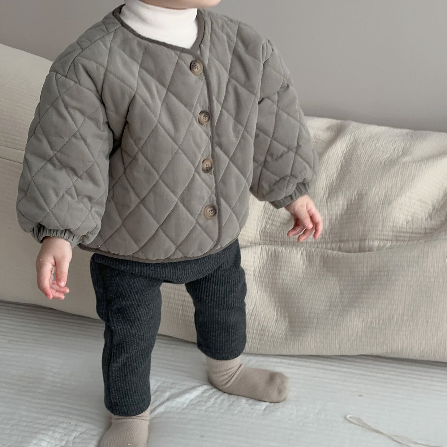 コンパクトにたたんでソファの端に置かれたベビー無地コットンコートの質感が分かる写真