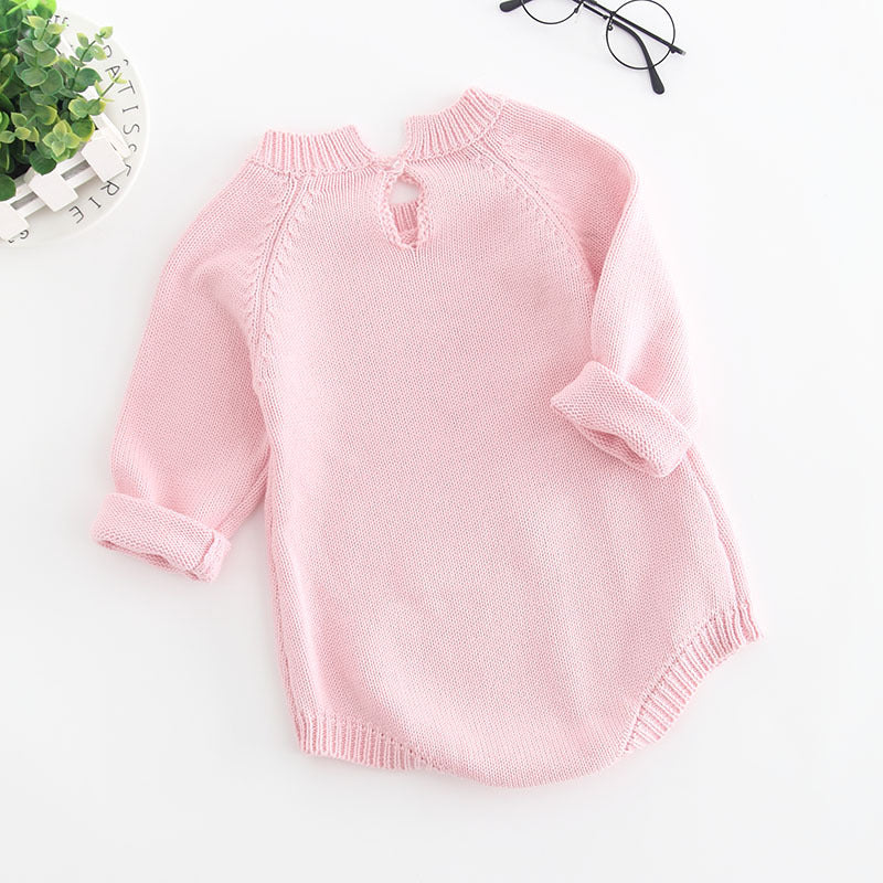 背中にボタンが一つ付いたピンクのニットベビーボディスーツを後ろ向きで写した全体イメージ