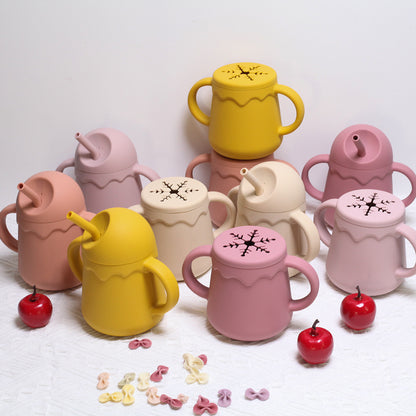 ピンク・イエローなどのシリコン2in1ベビーカップとスナックをテーブルに並べた画像（こぼれにくいシリコンベビーカップ）
