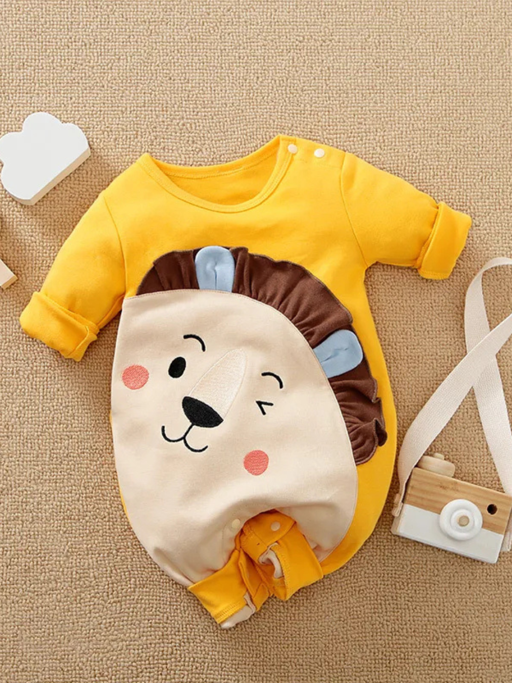 イエローのライオン柄ベビー長袖ロンパースを平置きで写した正面イメージ
