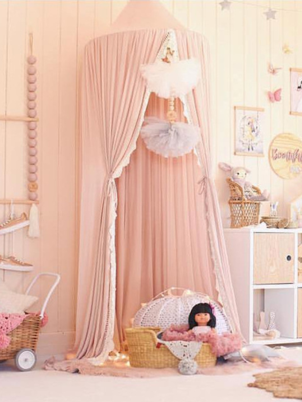 ピンクベージュのシフォンレース天蓋モスキートネットを床まで垂らし、かごや人形を置いた子ども部屋コーディネート（シフォンレース天蓋モスキートネット）
