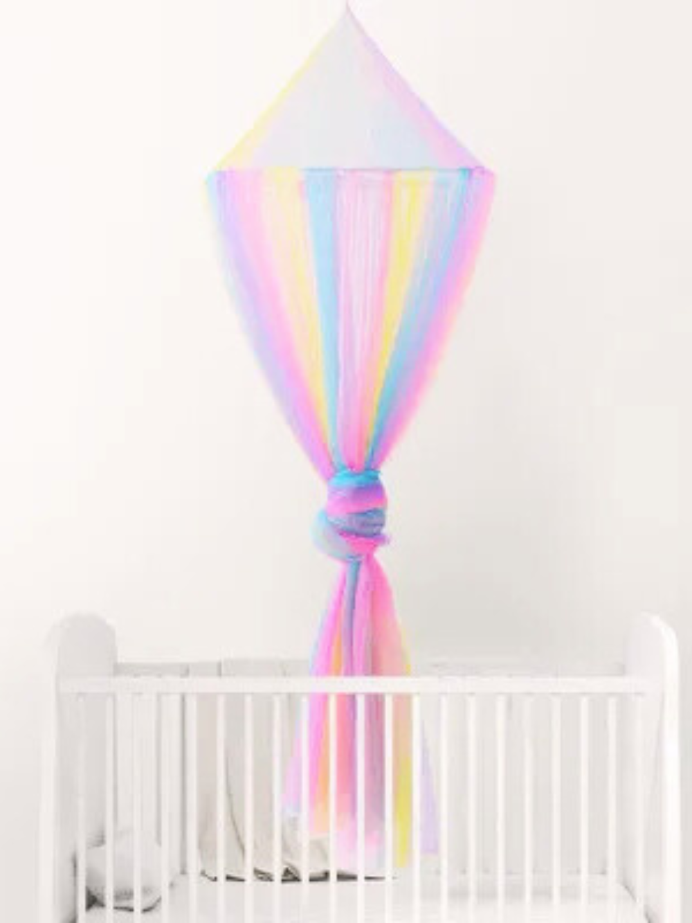 ユニコーンカラーのレインボーメッシュ天蓋が白いベビーベッドの上でふんわり広がる夢かわいい子ども部屋コーディネート（ユニコーンカラー ベビーモスキートネット）
