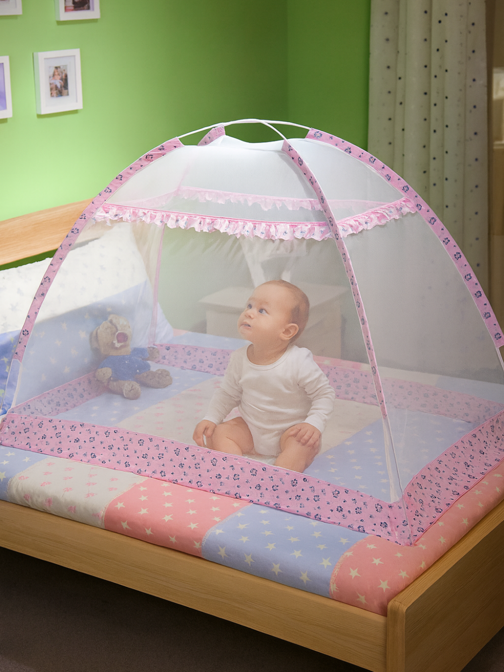 ピンクの縁取りが付いたユルト型ポップアップベビー蚊帳の中で、赤ちゃんがおすわりして遊んでいる様子（折りたたみベビー蚊帳・お昼寝スペース）
