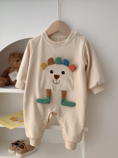 カラフルなタテガミ付きアニマルモチーフのベージュ長袖ベビーロンパースをハンガーに掛けた全身ショット
