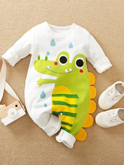 ベージュの床にワニプリント長袖ベビーロンパースと小さなシューズを並べたコーディネートイメージ
