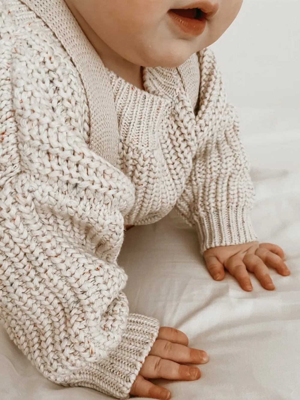 オフホワイトのベビー長袖ニットプルオーバーを着た赤ちゃんのハイハイ姿
