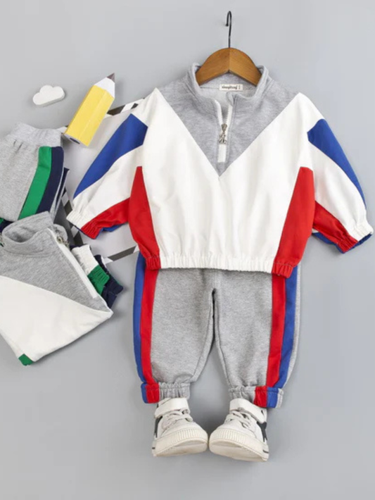 レッドとブルー配色トップスとグレー長ズボンにスニーカーを合わせた男の子用スポーツセットアップコーデ
