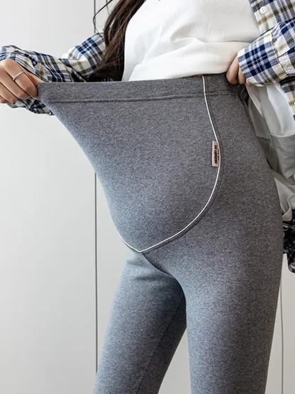 ダークグレーのマタニティレギンスのウエスト部分を引っ張って伸縮性と腹部サポートを示す着用アップ
