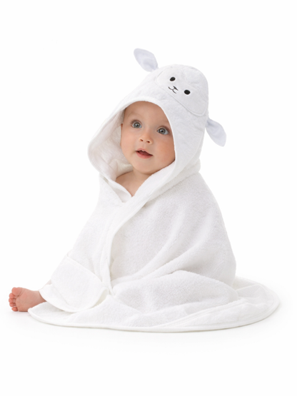 白いスタジオ背景で、ひつじ顔のフード付き白いベビーバスタオルに包まれて座っている赤ちゃん。均一な照明で、清潔感のある商品イメージ。
