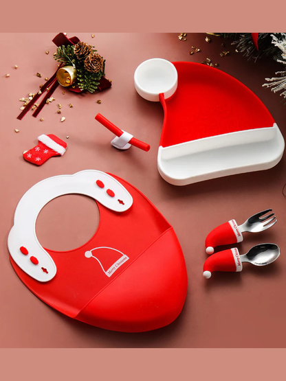 クリスマスモチーフのベビー食器セット一式（サンタ帽形プレート、ビブ、スプーン、フォーク）を俯瞰で並べたイメージ
