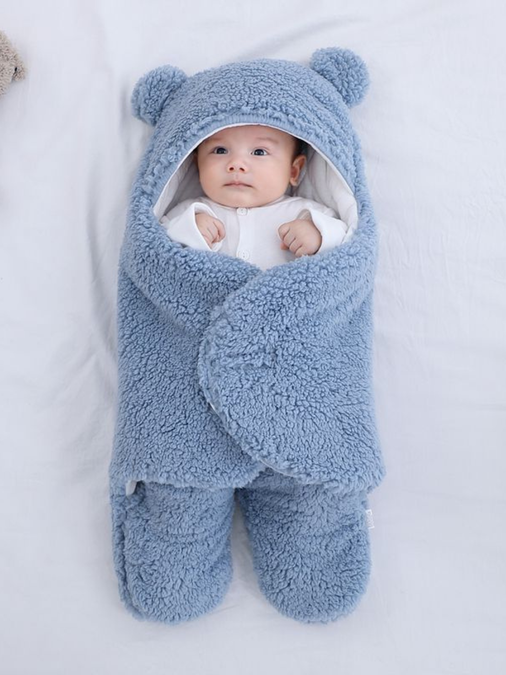 ライトブルーカラーのベビー寝袋スリーパーをベッドの上に広げた全体画像
