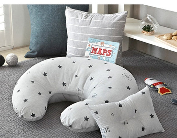 リビングのソファにインテリアクッションとして置かれたU字型授乳枕のイメージ画像  
