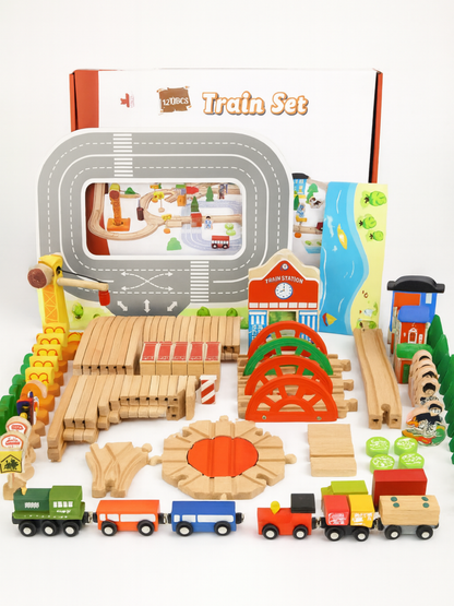 木製レール列車セット一式が白いスタジオ背景の上に並べられている様子。カーブレールや橋、駅舎、信号、標識、クレーン、木製の列車と貨車など120ピースのパーツがカラフルに配置されている。
