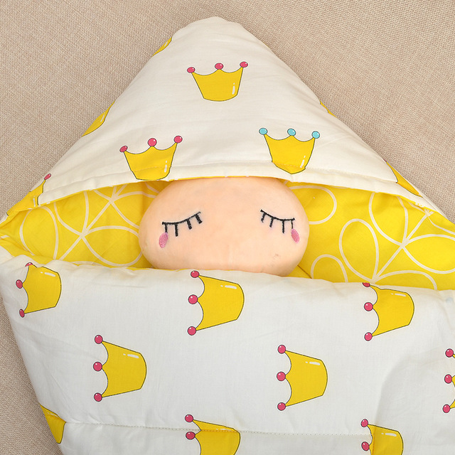 王冠柄イエローのベビーおくるみにくるまれて眠る赤ちゃんのアップ画像（ベビーおくるみ 王冠柄 ブランケット）
