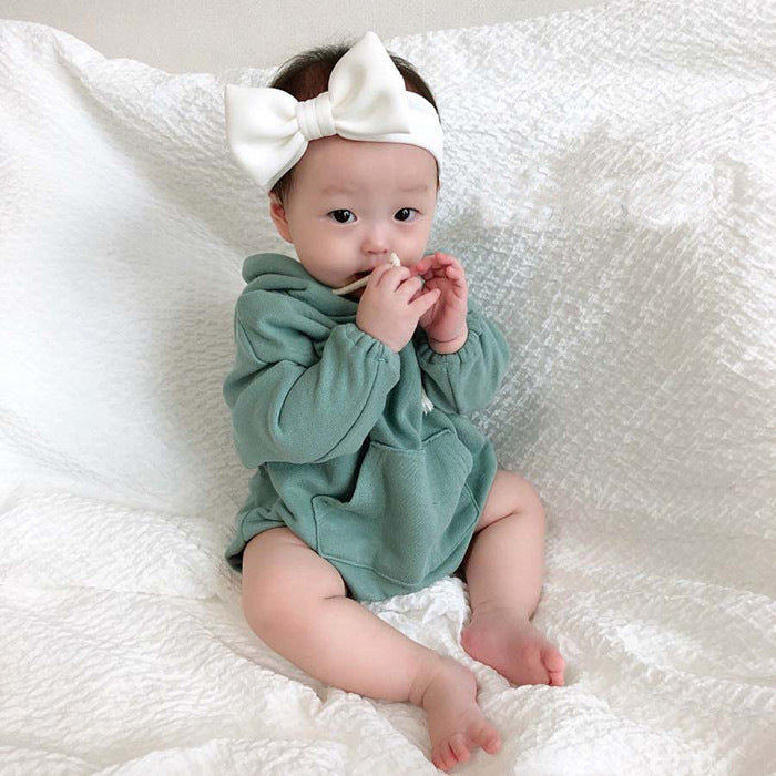 グリーンのフード付きコットンベビーボディスーツを着て正面を向いて座っている赤ちゃんの写真
