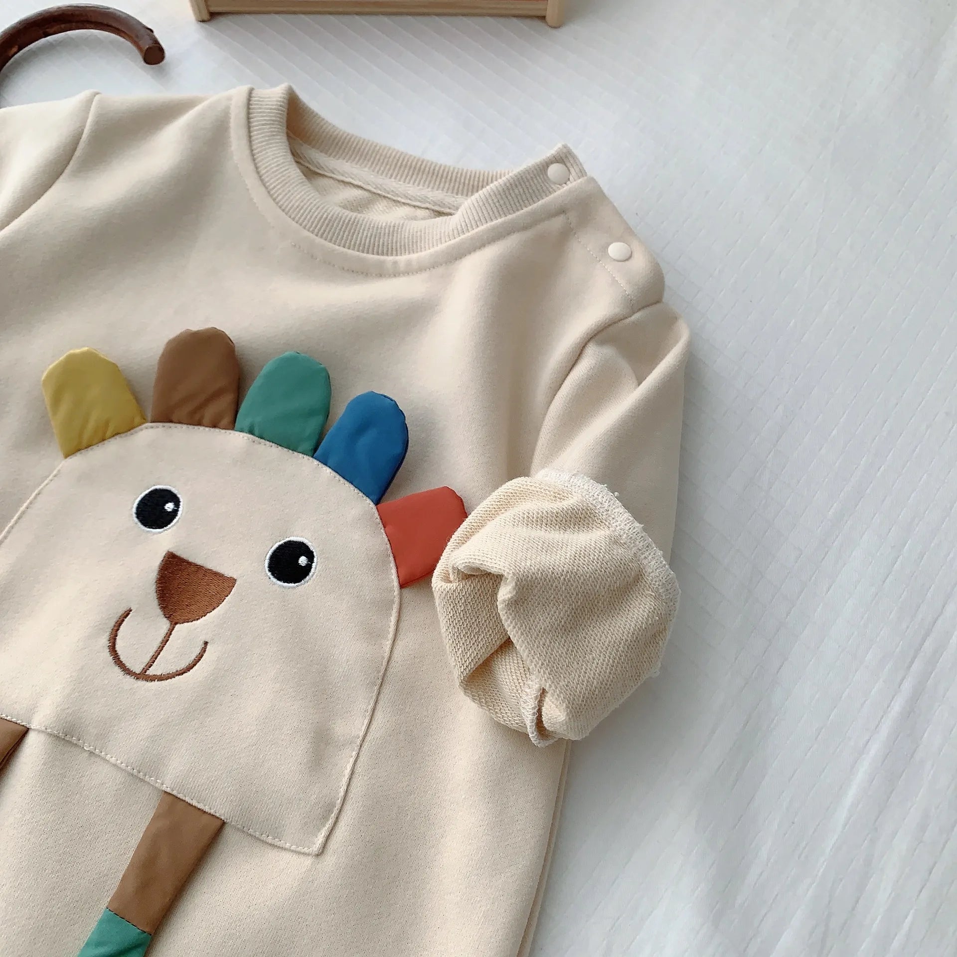 袖口リブと笑顔のアニマルフェイスが見えるベージュ長袖ロンパース上半身のイメージ
