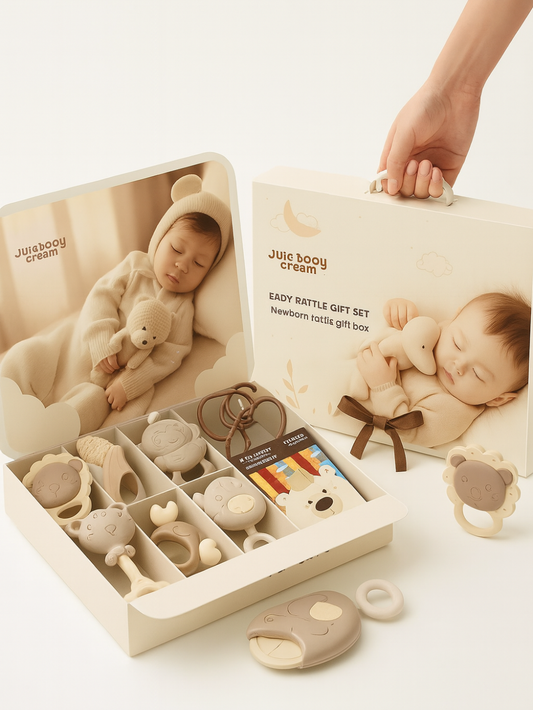 クリーム色のギフトボックスを開いた状態で、寝ている赤ちゃんの写真付きパッケージと、くまや動物モチーフのラトルや歯固めが整然と並んだ新生児用ベビーラトルギフトセットを柔らかなベージュトーンで撮影した商品画像
