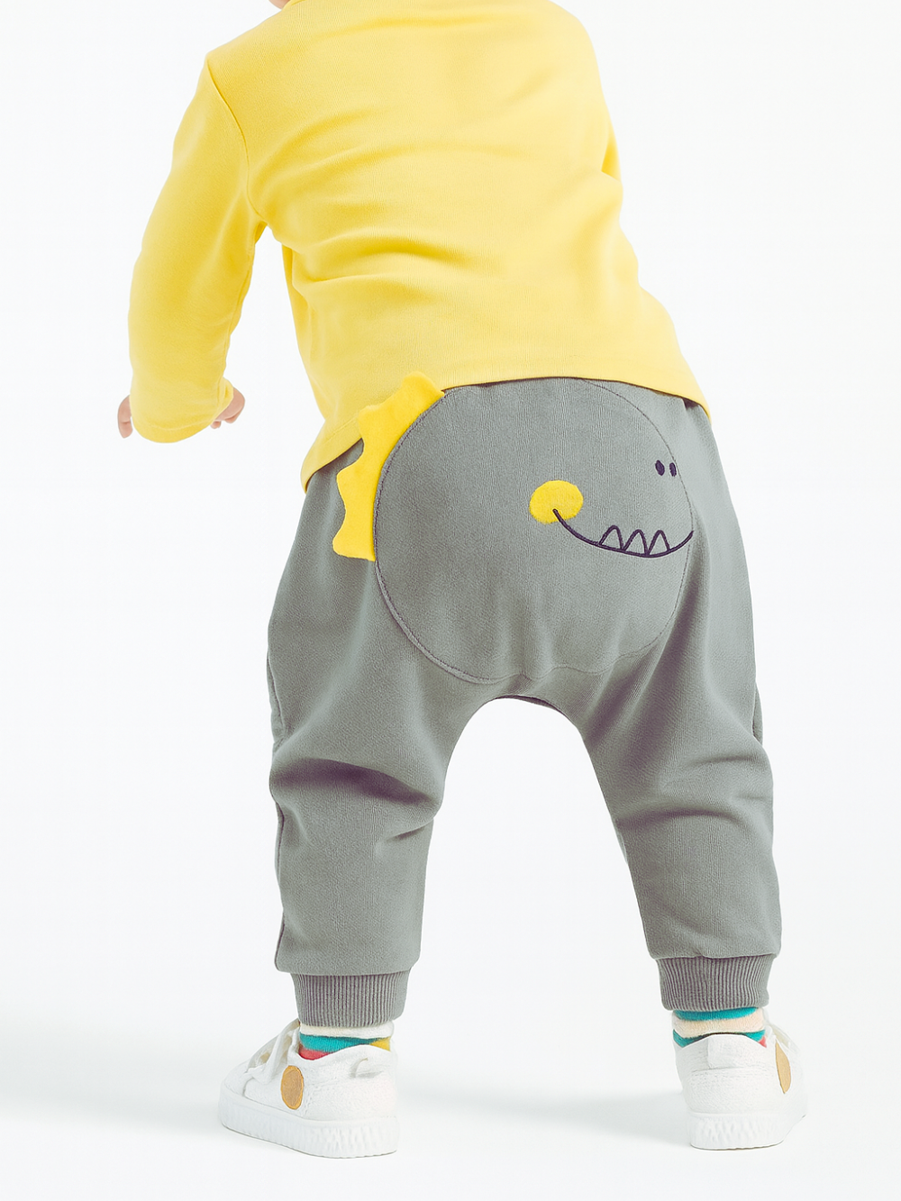 バックプリント恐竜デザインが目立つグレーPPパンツを履くベビーの後ろ姿
