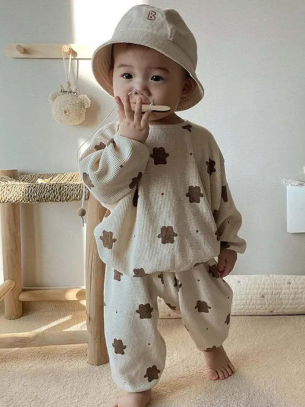 バケットハットをかぶった子どもがくま柄スウェット上下セットを着て立っている正面ショット
