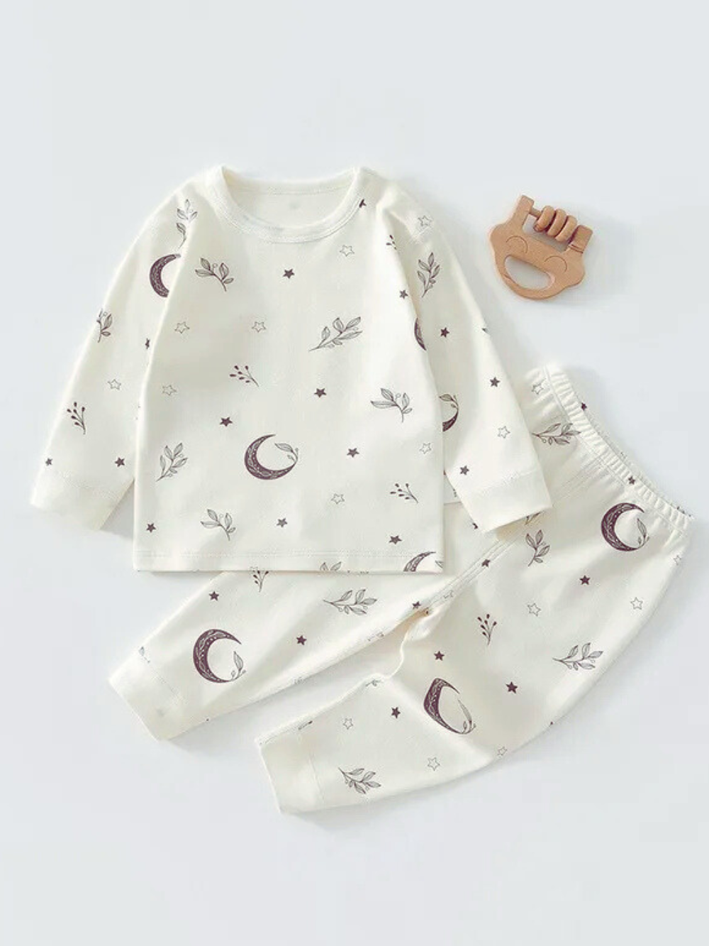 ホワイト地に月や星と小さな枝モチーフが総柄で描かれた長袖トップスとロングパンツのベビーパジャマ上下セット
