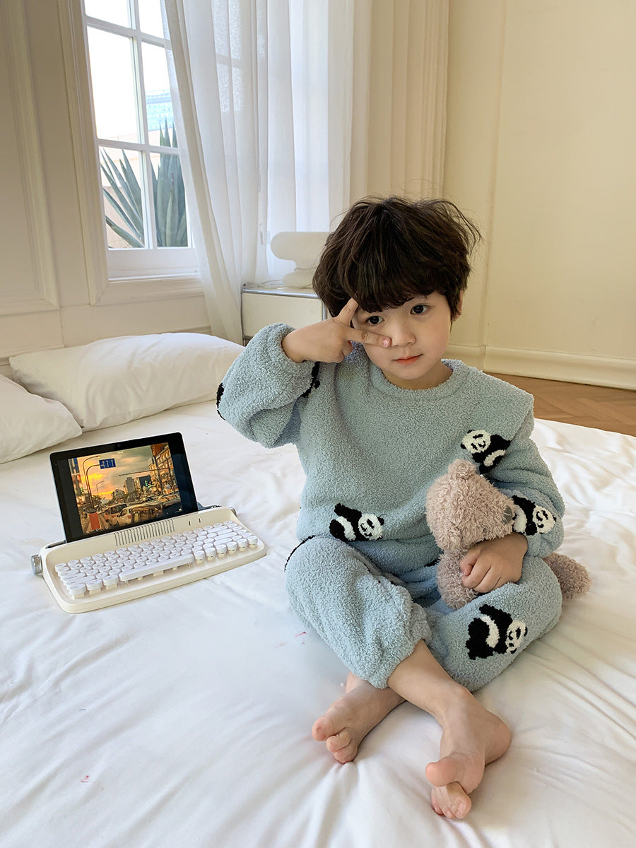 ブルーのアニマル柄コットンベロアパジャマ上下を着た子どもがベッドの上に座っている様子
