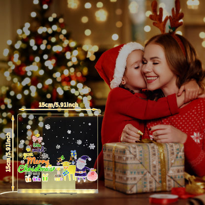 クリスマスツリーの前で子どもたちがLEDアクリルボードのカラフルな数字と文字の光を見つめている夜の雰囲気の写真
