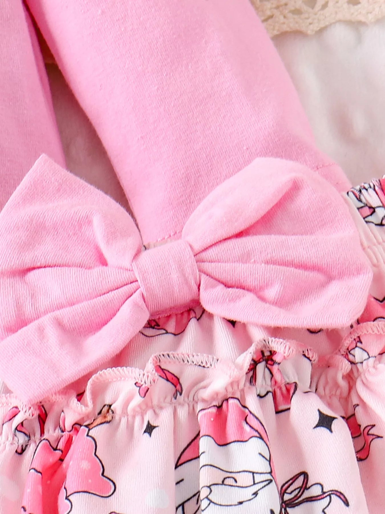 ウエスト部分の大きなピンクリボンとサンタ柄スカートのフリルディテールが映えるベビークリスマスコーデクローズアップ

