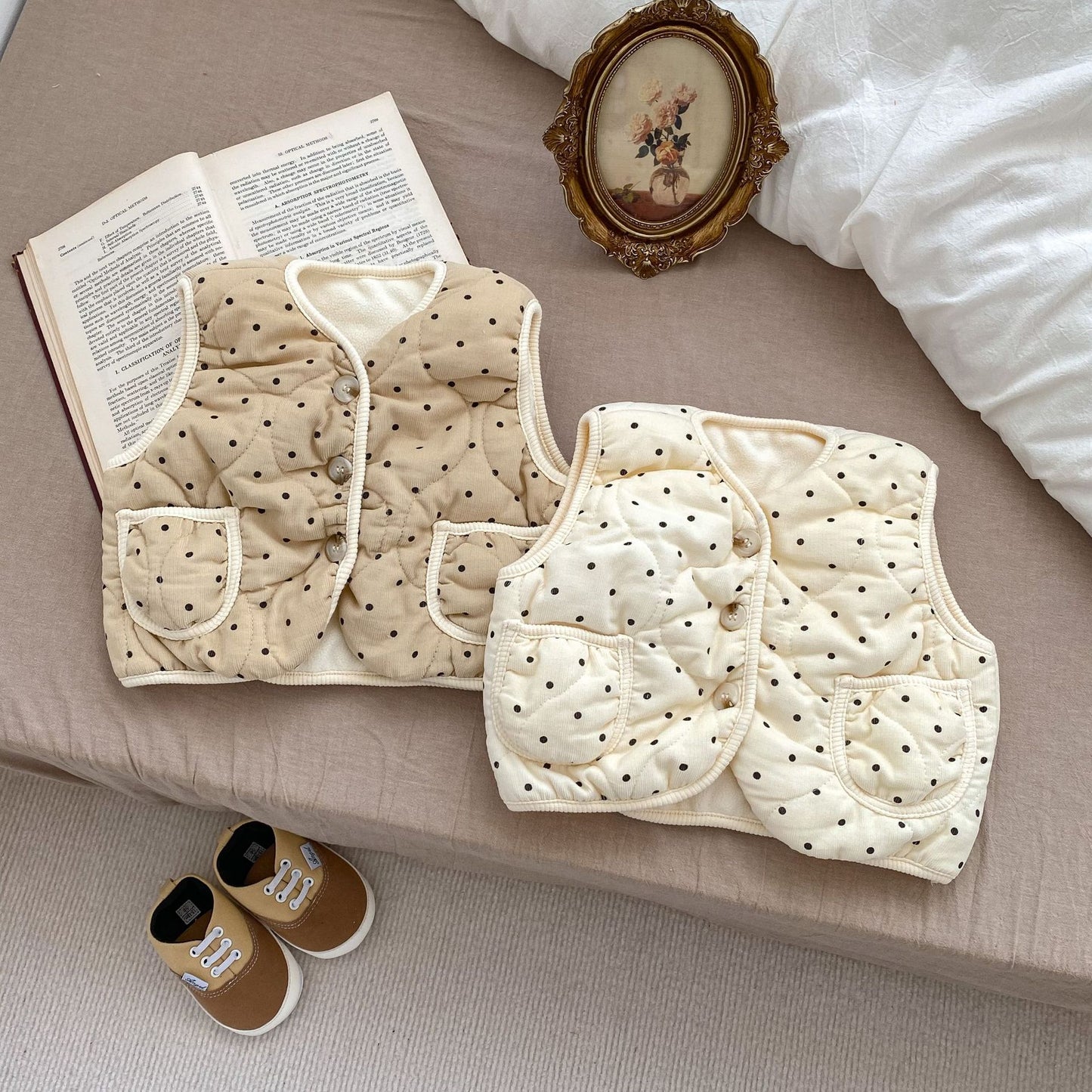 ベッドの上に並べられたドット柄コットンベビーベストカーキカラー
