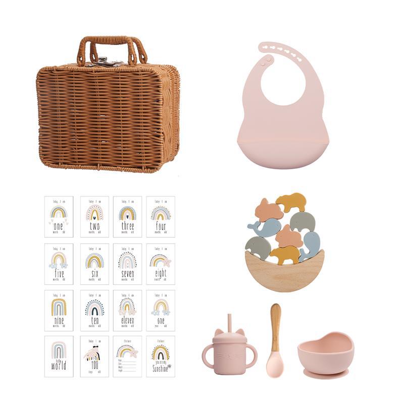 ラタン風バスケットとピンクのシリコンビブ、レインボーカード、アニマルスタッキングおもちゃ入りボウル、ピンクのシリコンカップとスプーン＆ボウルが並んだセット画像（ベビー用シリコン知育＆テーブルウェアスーツ）
