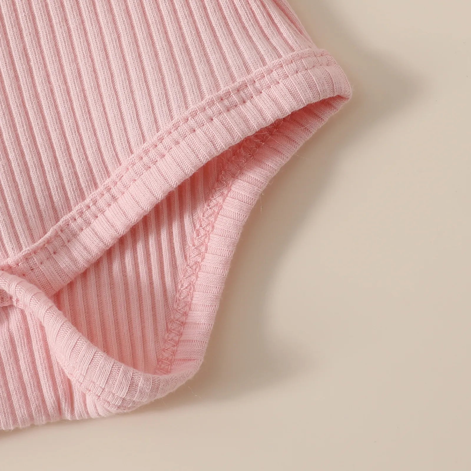 ピンクロンパースのリブ素材と縫製がわかる生地アップ
