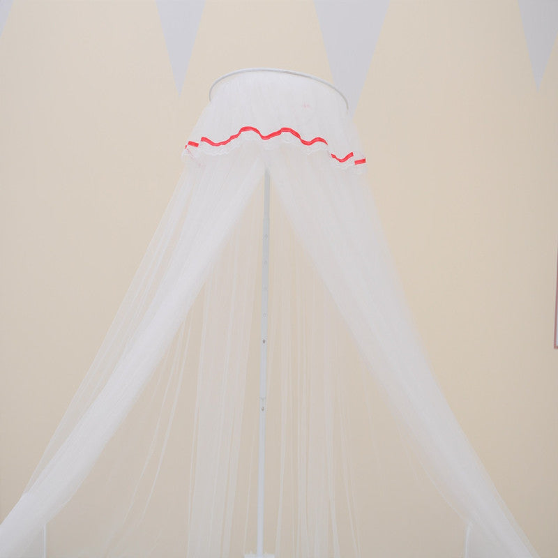 淡いベージュの壁を背景に、頂点から扇状に広がるホワイトメッシュのベビーベッド用モスキートネットをアップで写したカット（パレス風ホワイト蚊帳）
