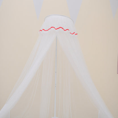 淡いベージュの壁を背景に、頂点から扇状に広がるホワイトメッシュのベビーベッド用モスキートネットをアップで写したカット（パレス風ホワイト蚊帳）
