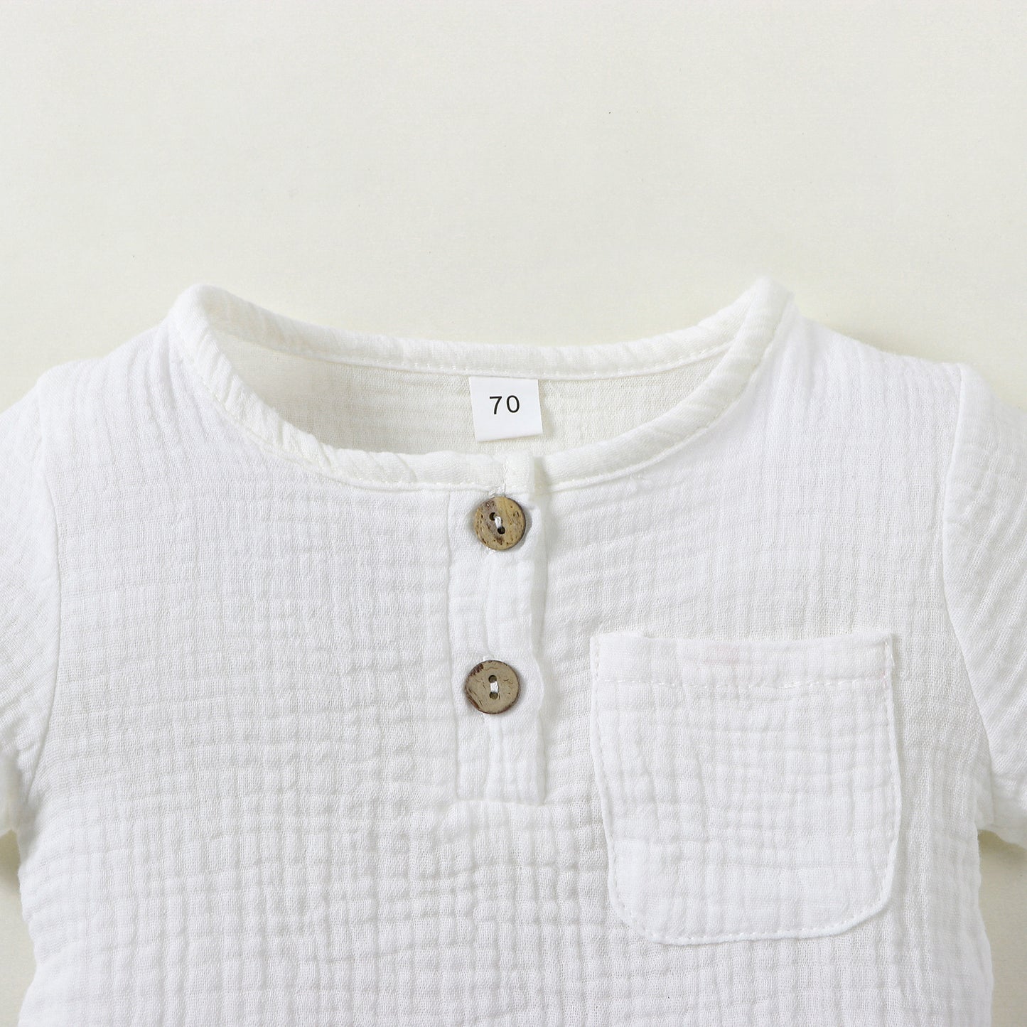 ホワイト半袖トップスの前ボタンと胸ポケットのディテール
