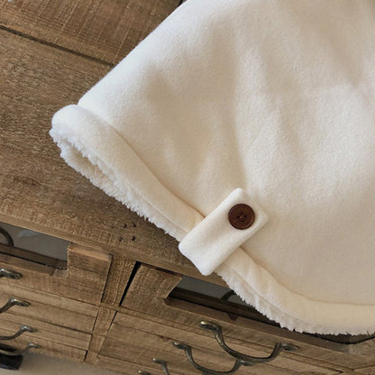 前ボタンと裾ラインのカーブが分かるキッズケープアウターのディテール画像
