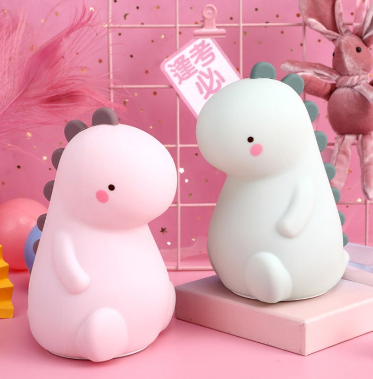 暗い部屋でピンクとグリーンの恐竜シリコンナイトライトが並んで光っている写真（ベビールーム用LEDナイトライト）
