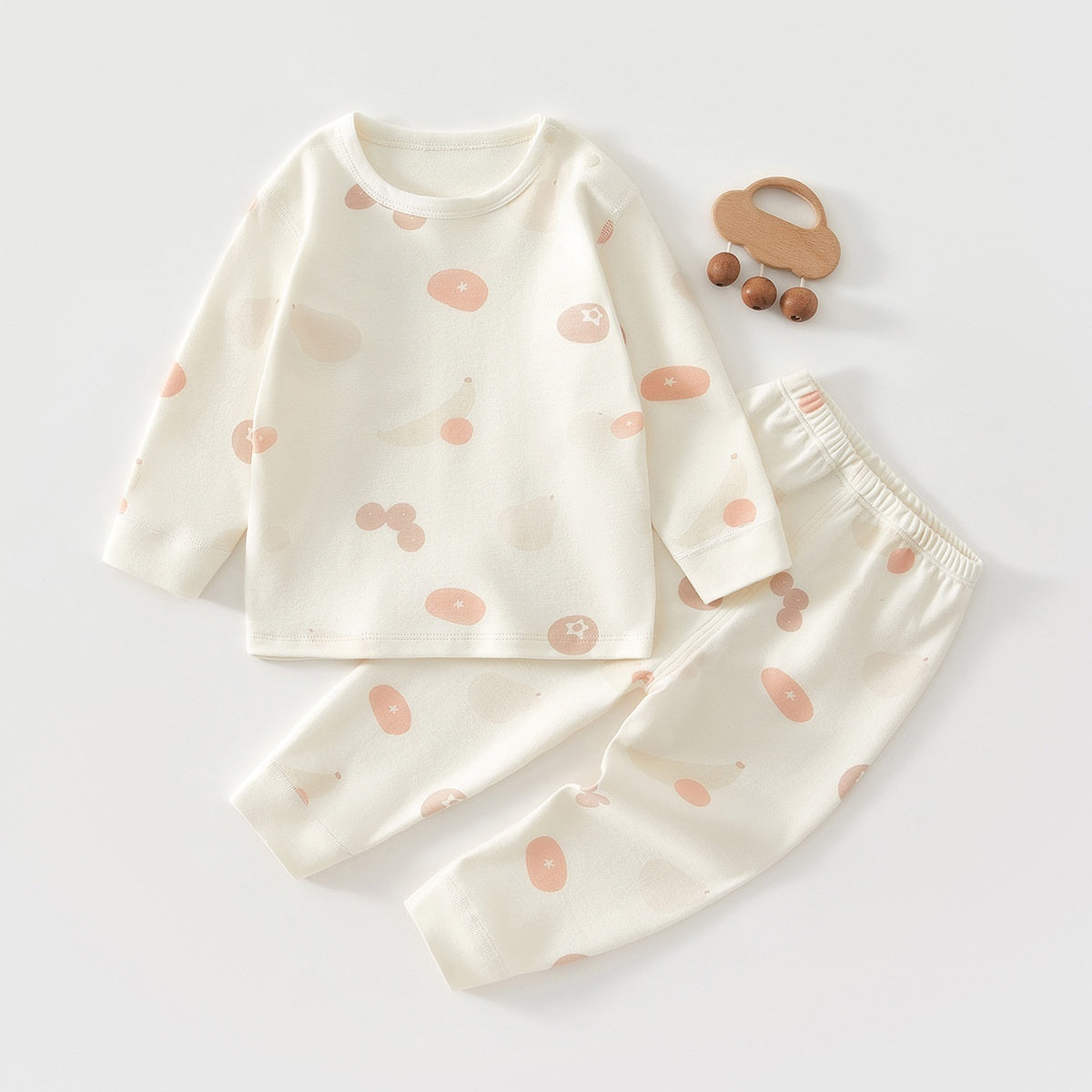 アイボリー地にやさしいピンクベージュ柄が散りばめられた長袖トップスとロングパンツのベビーパジャマ上下セット

