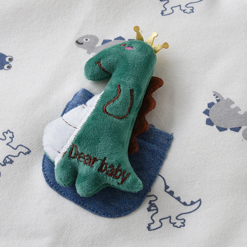 恐竜柄の生地の上に王冠付きグリーン恐竜ぬいぐるみトイを置いたアップ画像
