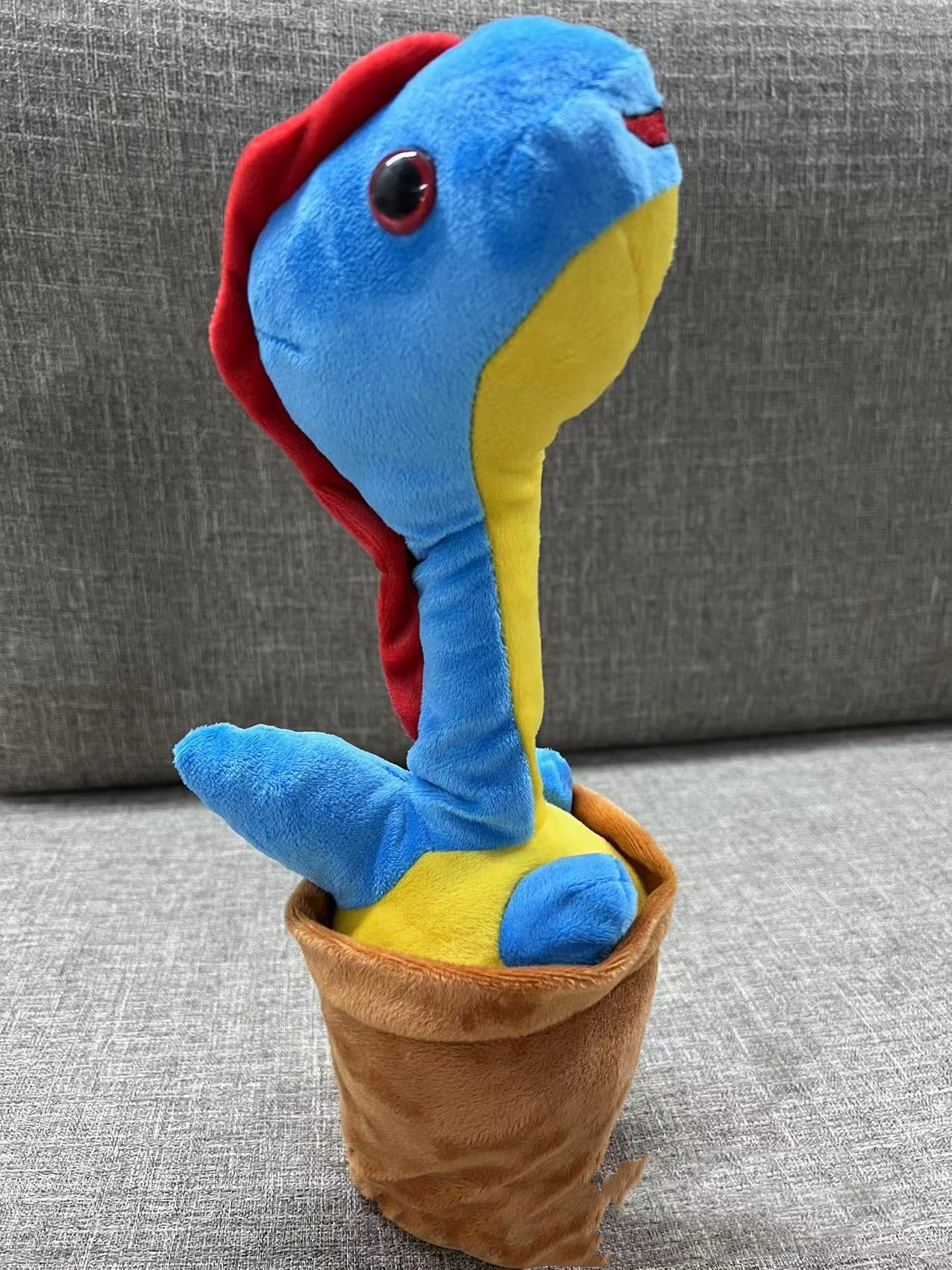 室内のソファ前に置いたブルーのポット型ダンシング恐竜トイ
