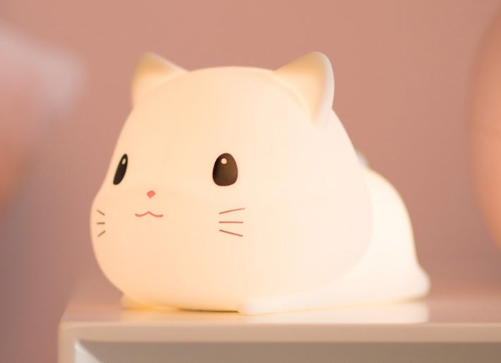 ベッドサイドテーブルの上で本と一緒に置かれたねこナイトライトのインテリア写真（インテリア照明）
