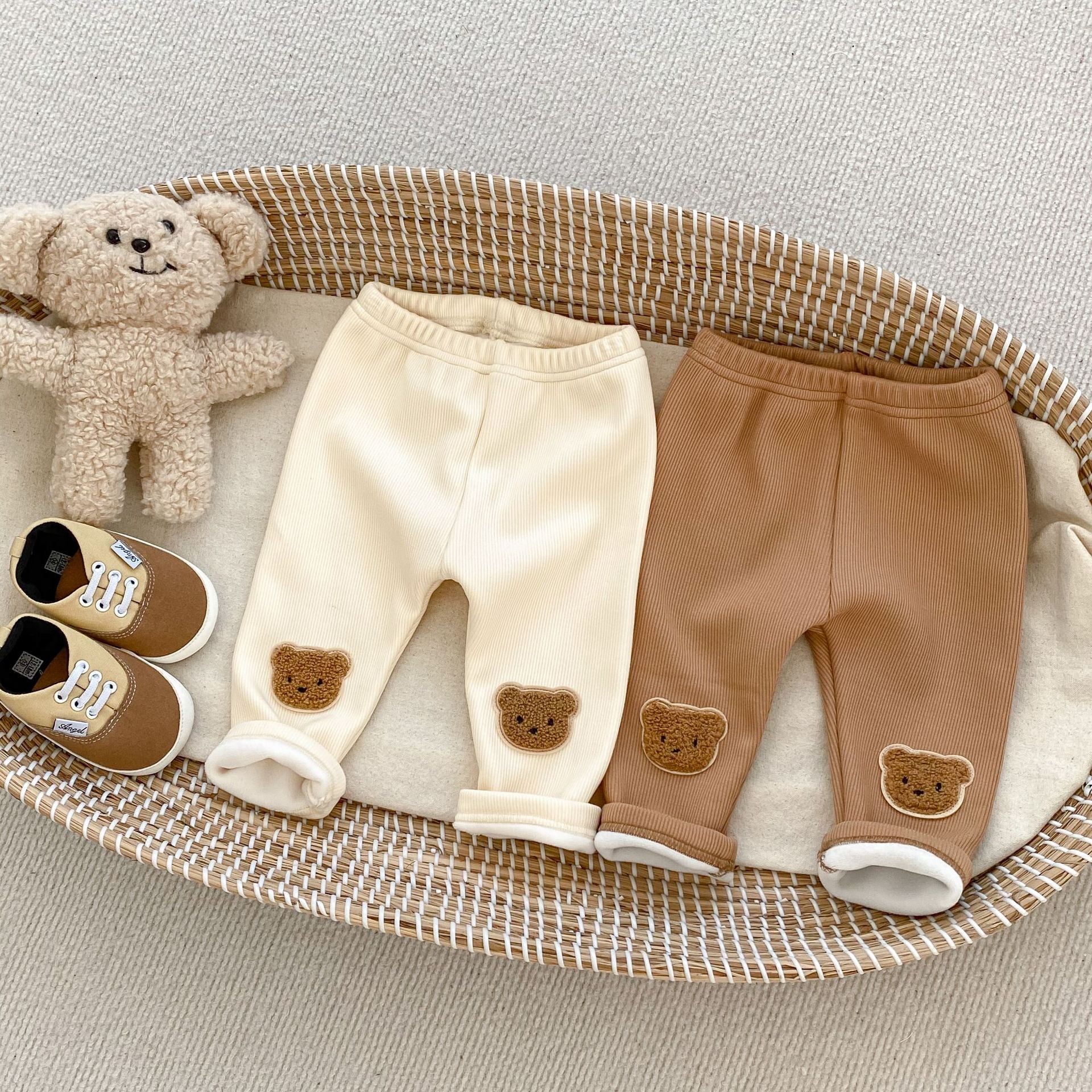 バスケットに並べられたミルクアプリコットとブラウンのくま刺繍コットンベビーロングパンツ
