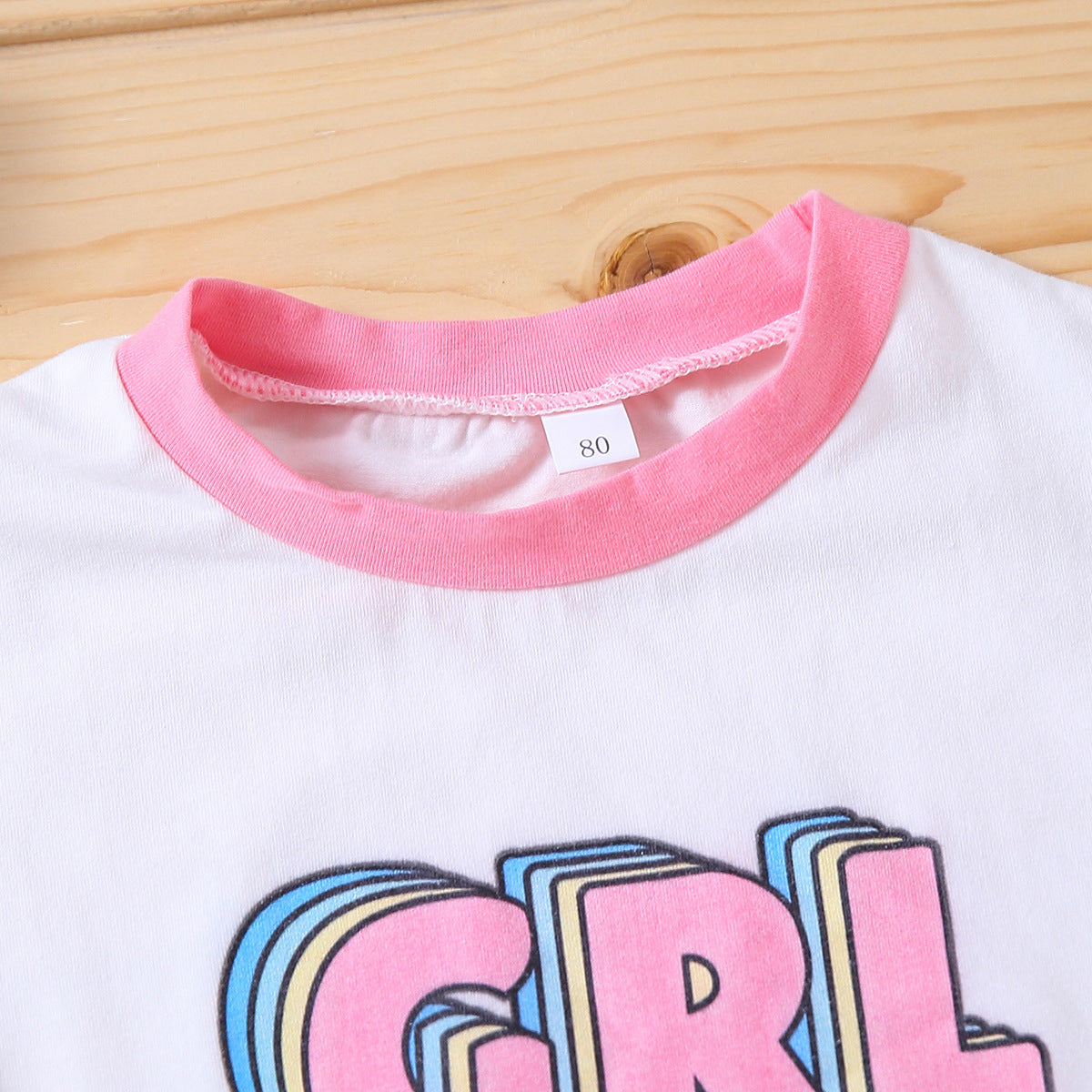 ピンクのリブ襟とロゴの一部が分かるベビーボディスーツ上部ディテール
