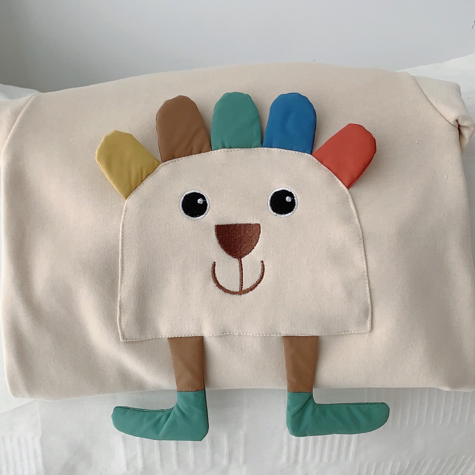 カラフルなタテガミと足つきアニマルモチーフを大きく写したベビーロンパース前身頃のアップ
