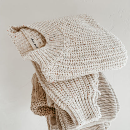 オフホワイトベビーセーターをきれいに畳んで積み重ねたディスプレイ
