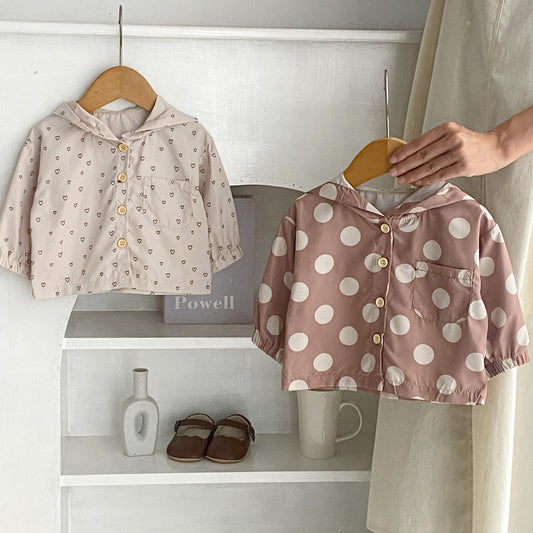 アプリコット色の水玉柄フード付きベビージャケットとライトブラウンのジャケットがハンガーに掛かっている写真
