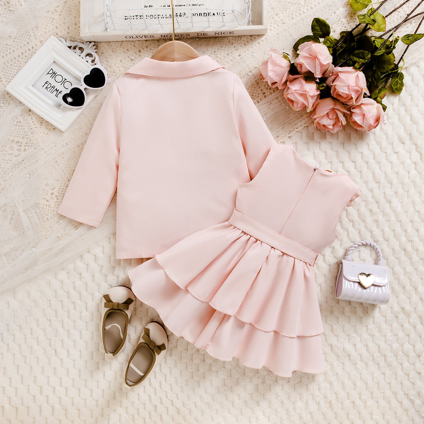 ピンクワンピースとコートにサンダルを合わせた女の子フォーマルコーデのフラットレイ
