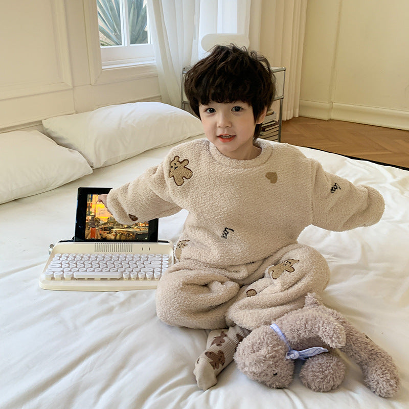 ベージュのふわもこパジャマを着た子どもがやわらかなブランケットを抱えてベッドの端に座っているシーン
