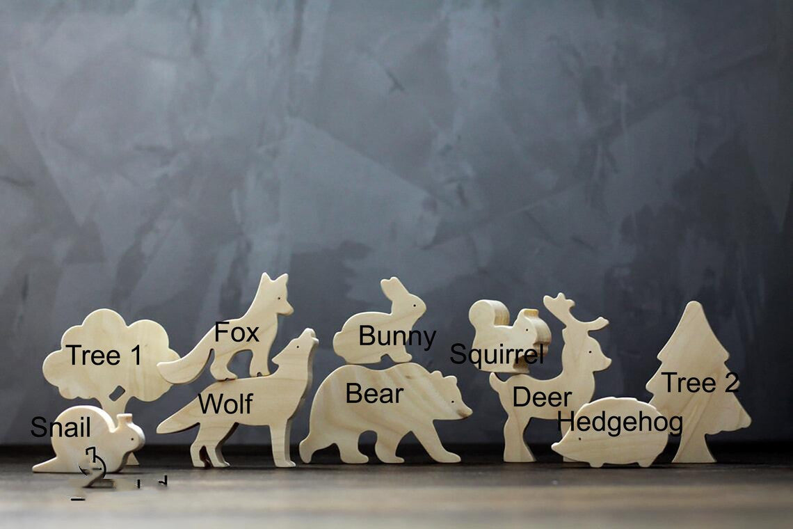暗めの背景で木製の森の動物フィギュア一式を横一列に並べた全体イメージ
