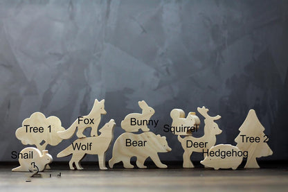 暗めの背景で木製の森の動物フィギュア一式を横一列に並べた全体イメージ
