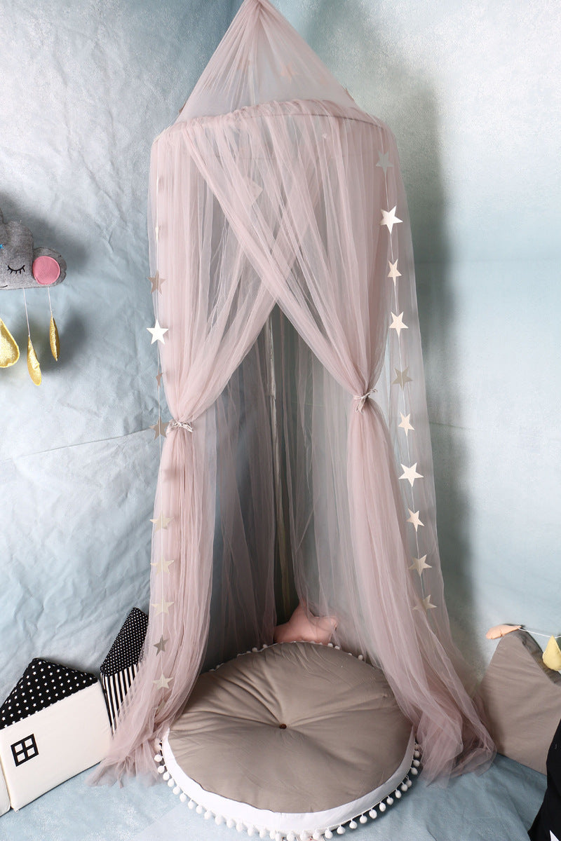くすみピンクのメッシュ天蓋を部屋のコーナーに吊り下げ、下にクッションとブランケットを敷いたガーリーなおこもりスペース（ピンクキャノピー プレイコーナー）
