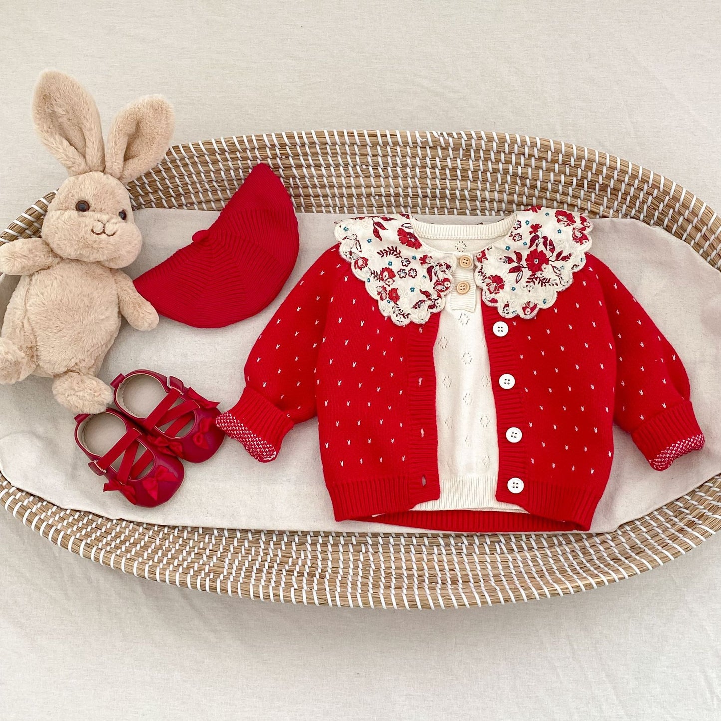 木のテーブルに並べられた赤い子供用カーディガン  